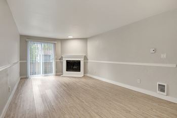 spacious living room with a fireplace and a sliding glass door with light-toned plank flooring at 2000 Lake Washington Apartments, Washington